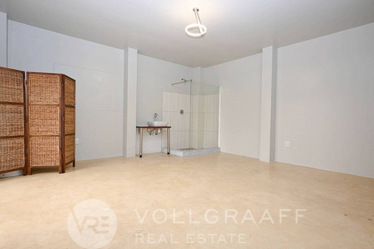 Spacious bedroom featuring an open-plan en-suite area with a walk-in shower and modern basin, offering a clean, minimalist aesthetic.