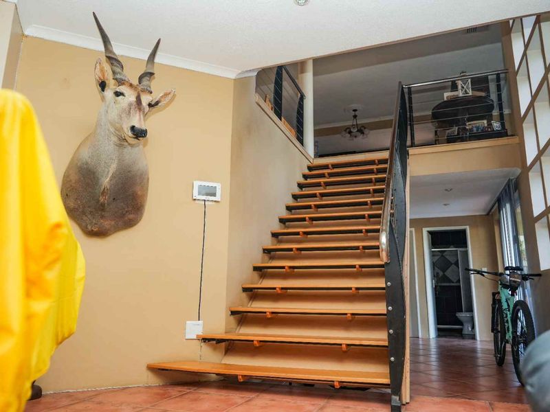 Entrance area featuring an open-tread staircase with metal handrails, leading to a mezzanine level with tiled flooring throughout.