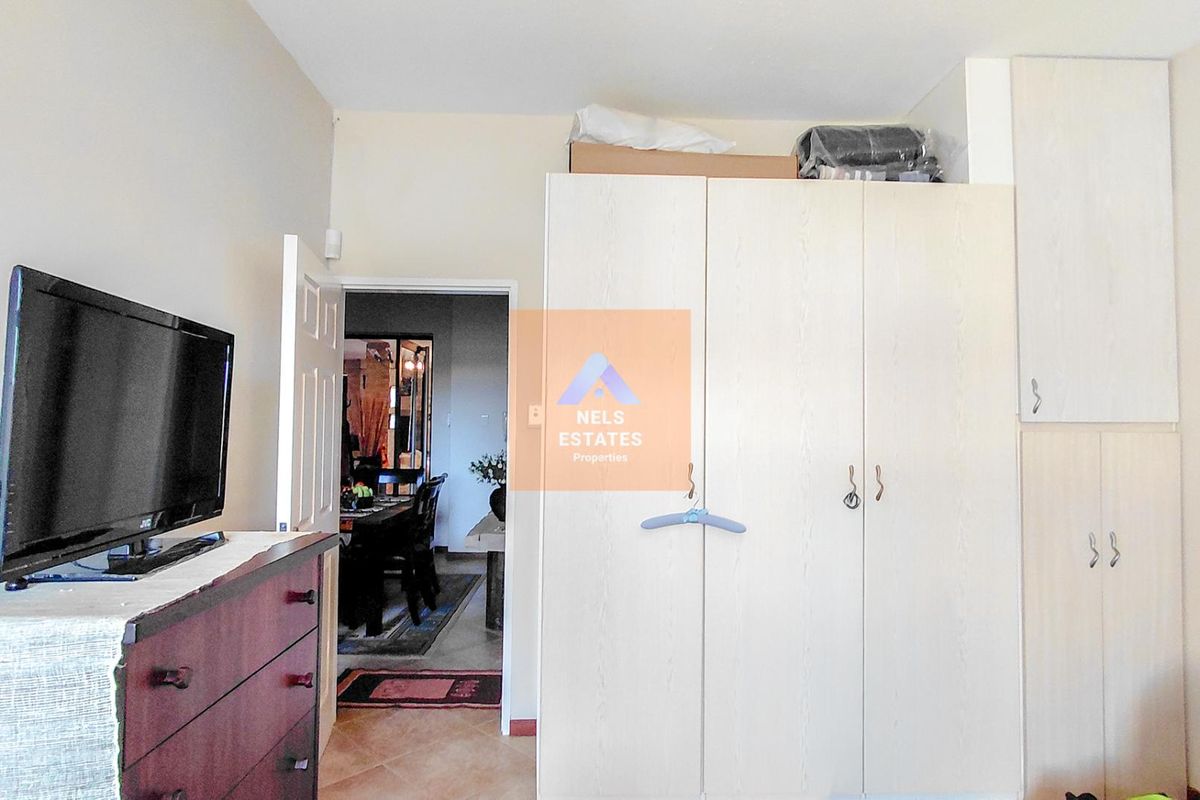 A bedroom featuring built-in cabinetry with overhead storage units and tiled flooring, providing functional storage space.