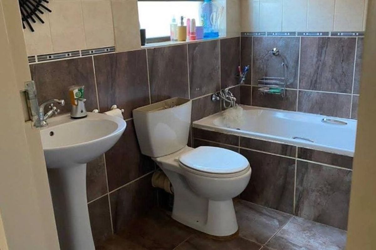 A functional bathroom featuring a pedestal basin, toilet, and a built-in bathtub with tiled finishes throughout.