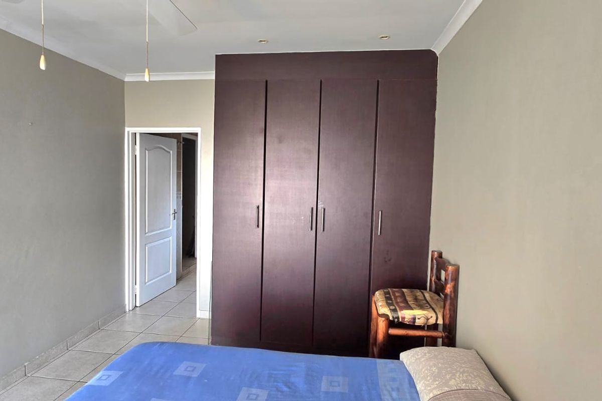 A bedroom featuring built-in dark wood cabinetry, tiled flooring, and recessed ceiling lighting, providing functional storage and a neutral living space.