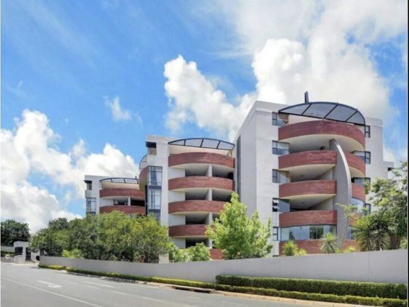Exterior view of a modern multi-story penthouse apartment building featuring distinctive curved balconies and brick architectural detailing.