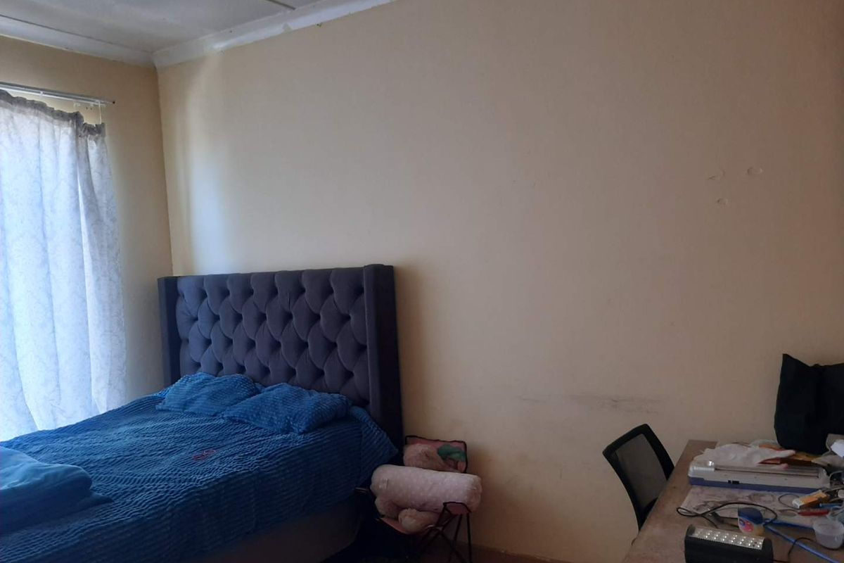 A bedroom featuring neutral wall tones and a window with installed curtain hardware, requiring minor cosmetic updates to improve the overall finish.