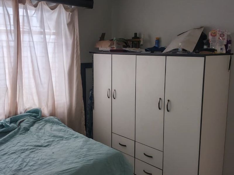 A bedroom featuring tiled flooring and a large built-in wardrobe with integrated drawers, providing ample storage space.