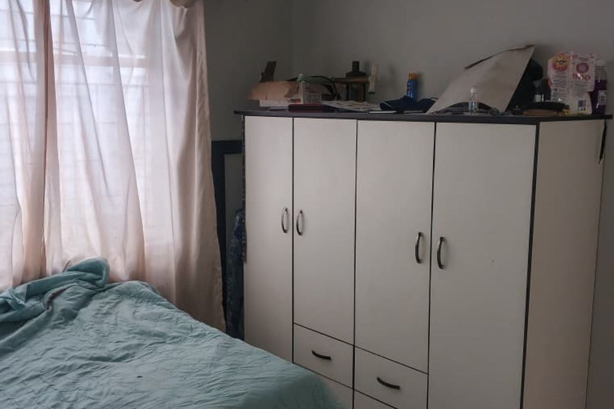 A bedroom featuring tiled flooring and a large built-in wardrobe with integrated drawers, providing ample storage space.