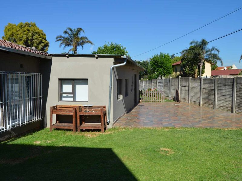 Rear exterior view featuring a tiled patio area, a well-maintained lawn, and secure precast concrete boundary walling.
