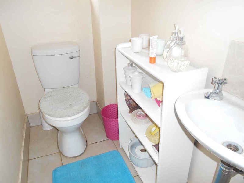 A compact bathroom featuring a standard toilet and a pedestal basin with tiled flooring.