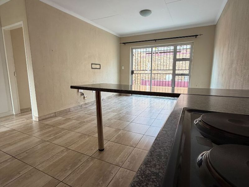 Open-plan kitchen and living area featuring tiled flooring, a built-in electric hob, and a sliding glass door leading to the exterior.