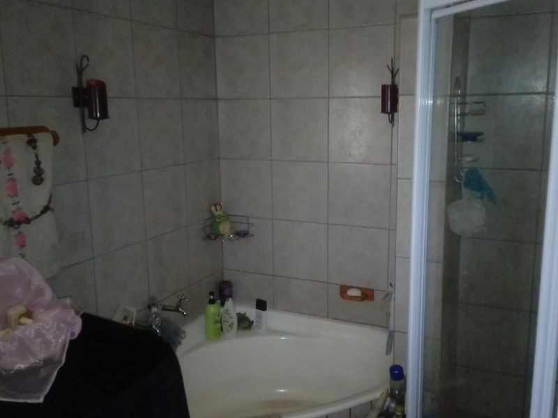 A bathroom featuring a corner bathtub, a separate shower enclosure, and neutral wall tiling. The space requires minor maintenance and cosmetic updates.