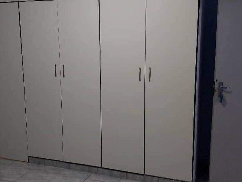 A bedroom featuring built-in cupboards with tiled flooring and a standard internal door, showing signs of wear and tear.