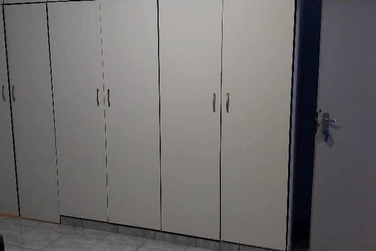 A bedroom featuring built-in cupboards with tiled flooring and a standard internal door, showing signs of wear and tear.