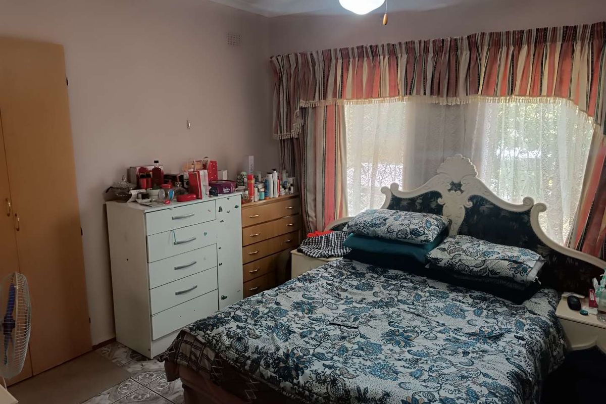A bedroom featuring tiled flooring, a built-in wardrobe, and a central ceiling light fixture, offering a functional space with potential for modernization.