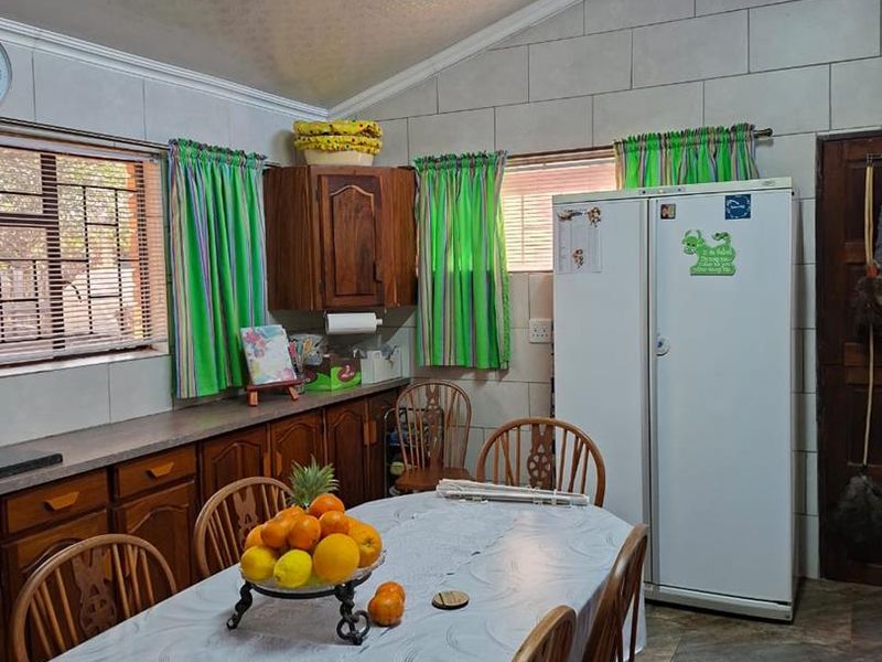 A functional kitchen featuring built-in wooden cabinetry, tiled walls, and tiled flooring under a vaulted ceiling, offering a traditional layout with ample storage space.