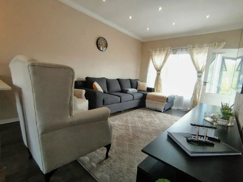 A comfortable living room featuring tiled flooring, recessed downlighting, and coved ceiling details, providing a functional and well-lit space for relaxation.
