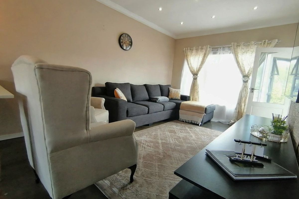 A comfortable living room featuring tiled flooring, recessed downlighting, and coved ceiling details, providing a functional and well-lit space for relaxation.