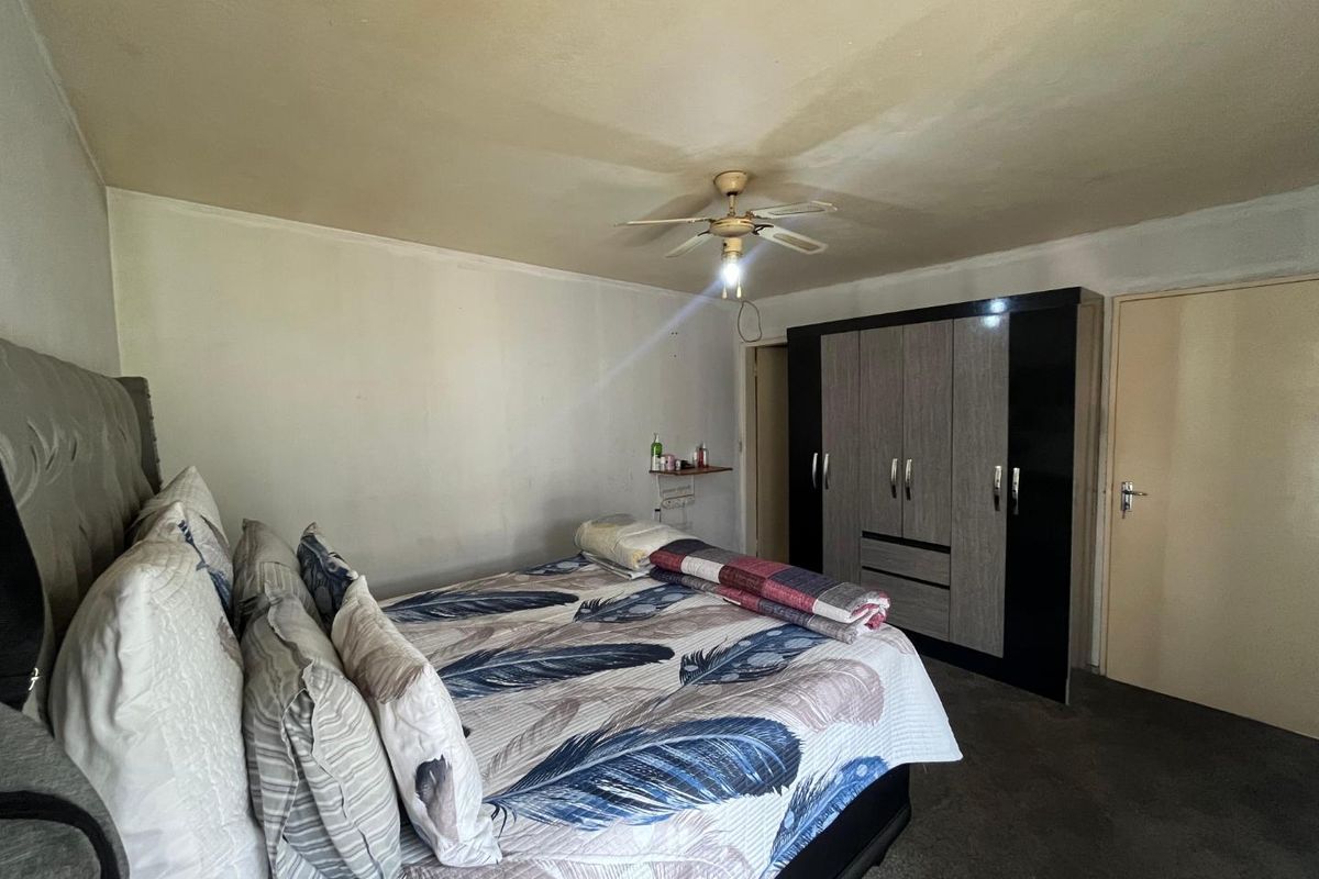 A bedroom featuring a ceiling fan and a built-in wardrobe, requiring cosmetic updates to the ceiling and wall finishes.