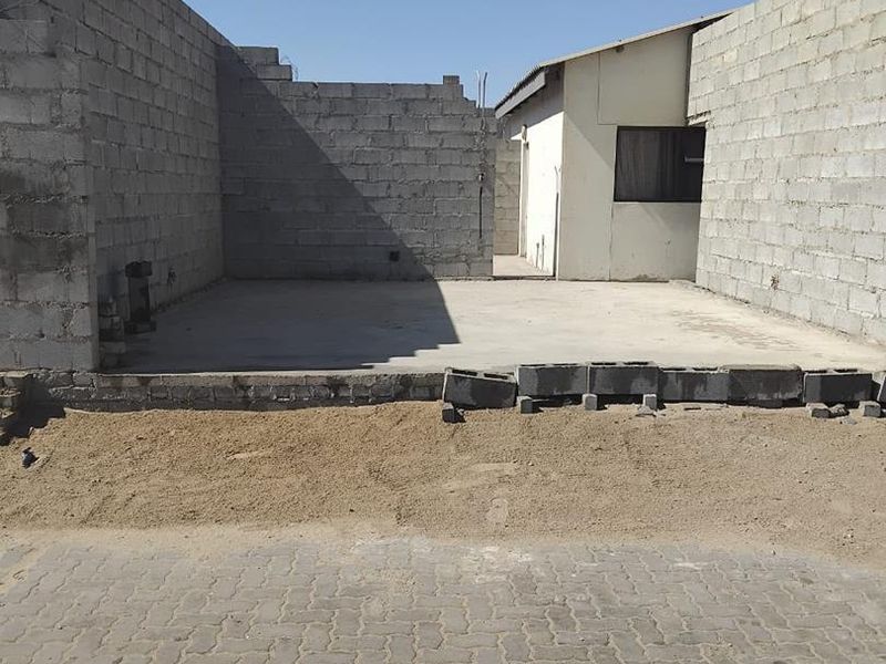 An unfinished exterior area featuring exposed concrete block walls and a concrete slab foundation, ready for further development or landscaping.