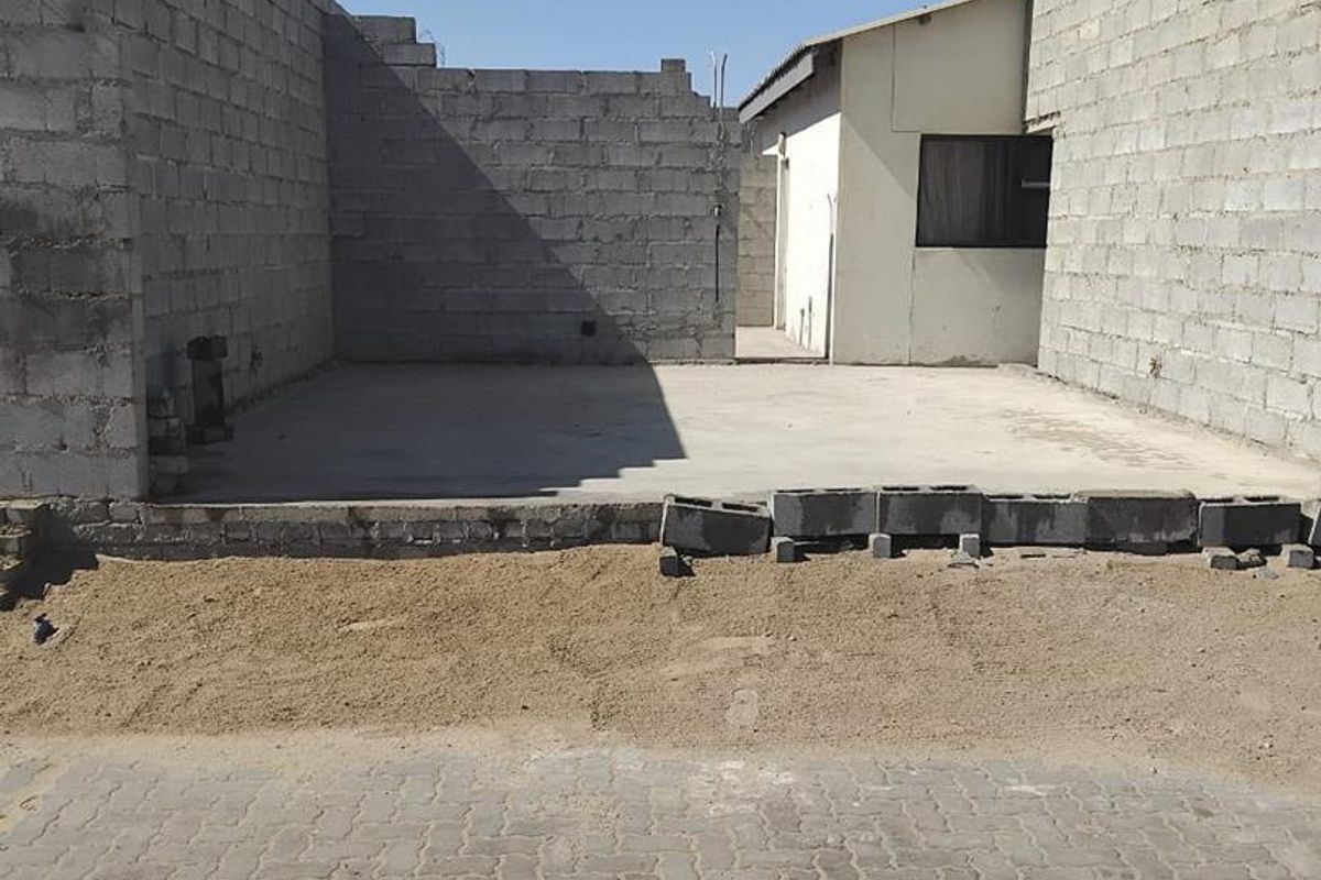 An unfinished exterior area featuring exposed concrete block walls and a concrete slab foundation, ready for further development or landscaping.
