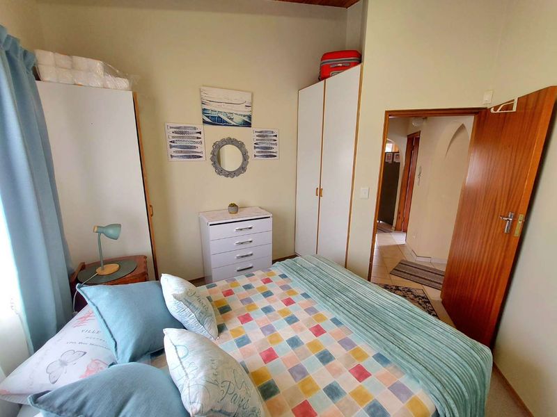 A functional bedroom featuring built-in cupboards and a wooden door, providing access to the hallway.
