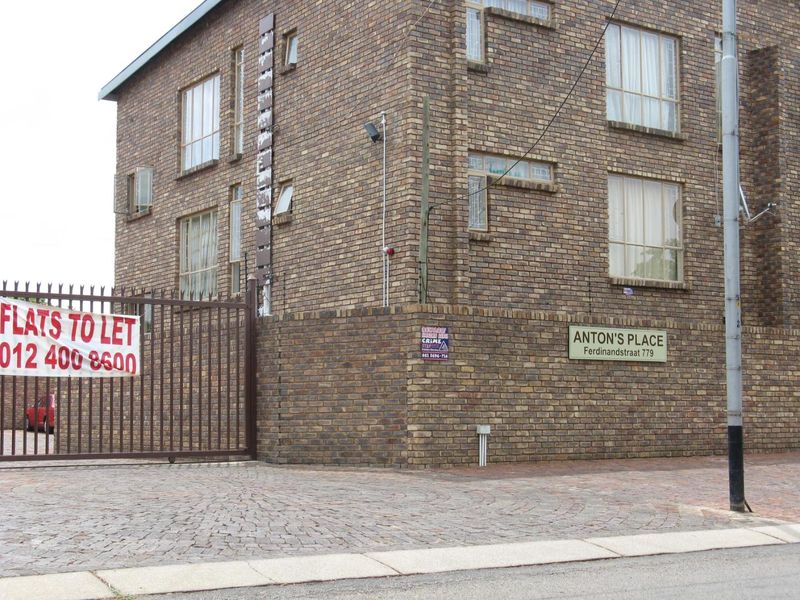 Exterior view of Anton's Place apartment building featuring a face brick facade, secure gated entrance, and paved driveway.