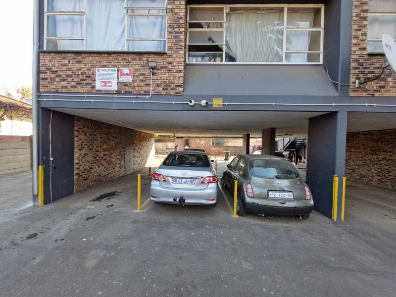 Covered parking area featuring exposed brick walls and concrete ceiling structure, providing sheltered off-street parking for residents.