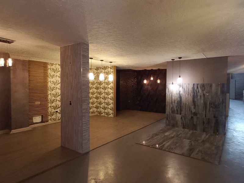 Spacious open-plan industrial interior featuring polished concrete flooring, decorative wall paneling, and modern pendant lighting fixtures throughout the expansive layout.
