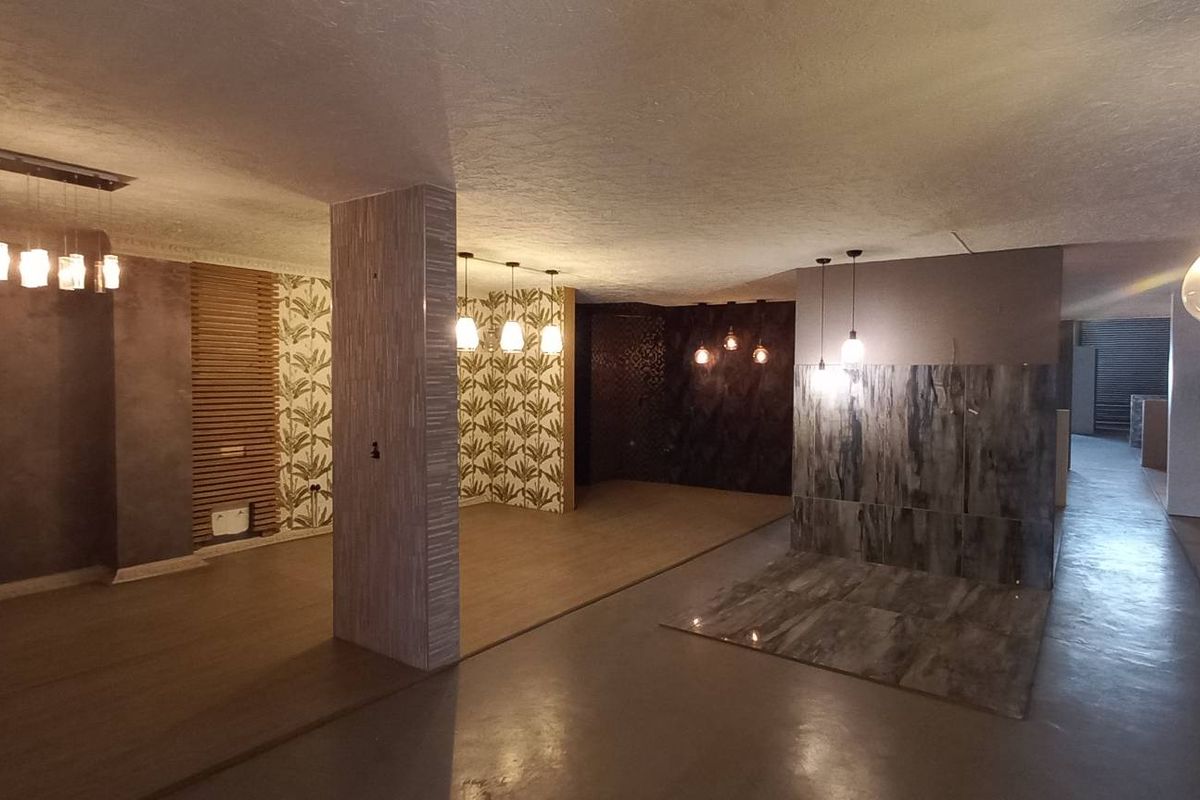 Spacious open-plan industrial interior featuring polished concrete flooring, decorative wall paneling, and modern pendant lighting fixtures throughout the expansive layout.