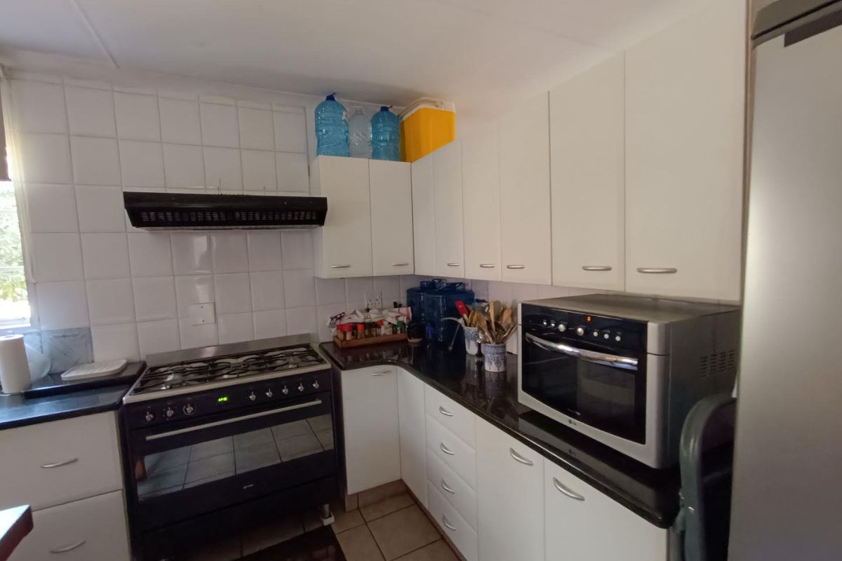 A functional kitchen featuring white cabinetry, dark countertops, a gas stove with extractor fan, and a built-in oven.