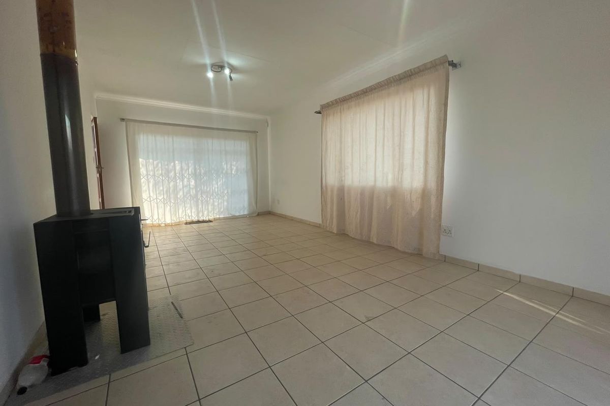 Spacious living area featuring neutral ceramic floor tiles and a built-in freestanding fireplace, offering a blank canvas for interior design.