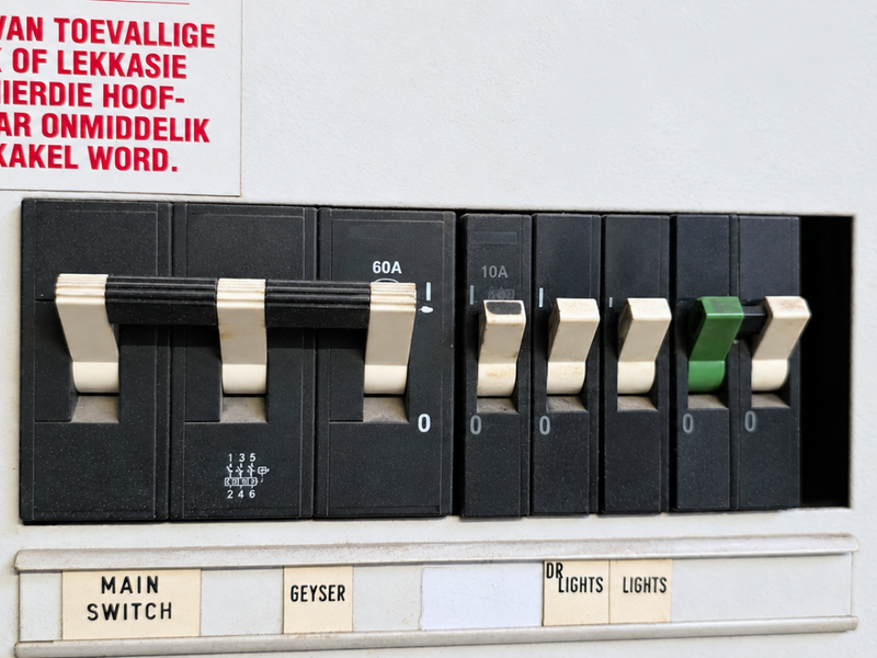 A close-up view of an electrical distribution board featuring a main switch and various circuit breakers for office power and lighting systems.