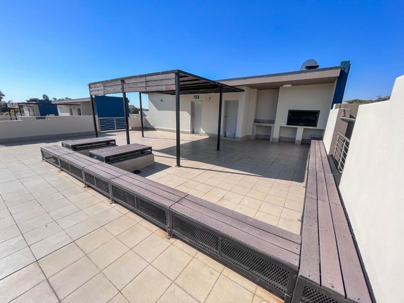 Spacious rooftop patio featuring a built-in braai, pergola, and integrated bench seating, offering an ideal outdoor entertainment area.
