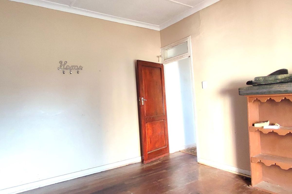 A vacant bedroom featuring original timber flooring, coved ceilings, and a solid timber door, offering a blank canvas for renovation.