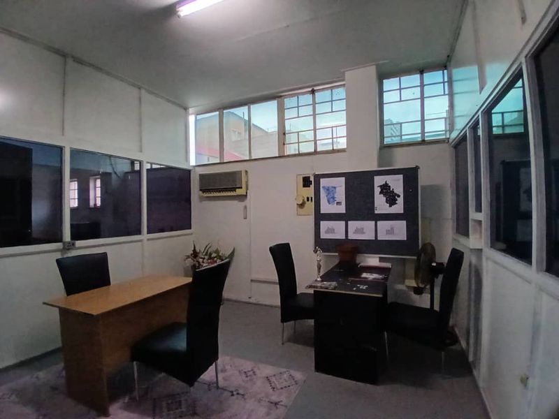 A functional office space featuring partitioned walls, aluminum-framed windows, and an integrated air conditioning unit, suitable for a professional work environment.