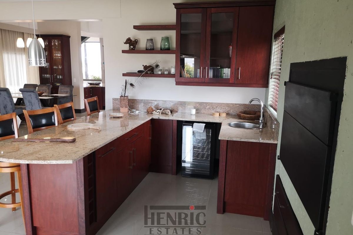 A well-appointed kitchen area featuring dark wood cabinetry, granite countertops, an integrated wine cooler, and a functional breakfast bar setup.