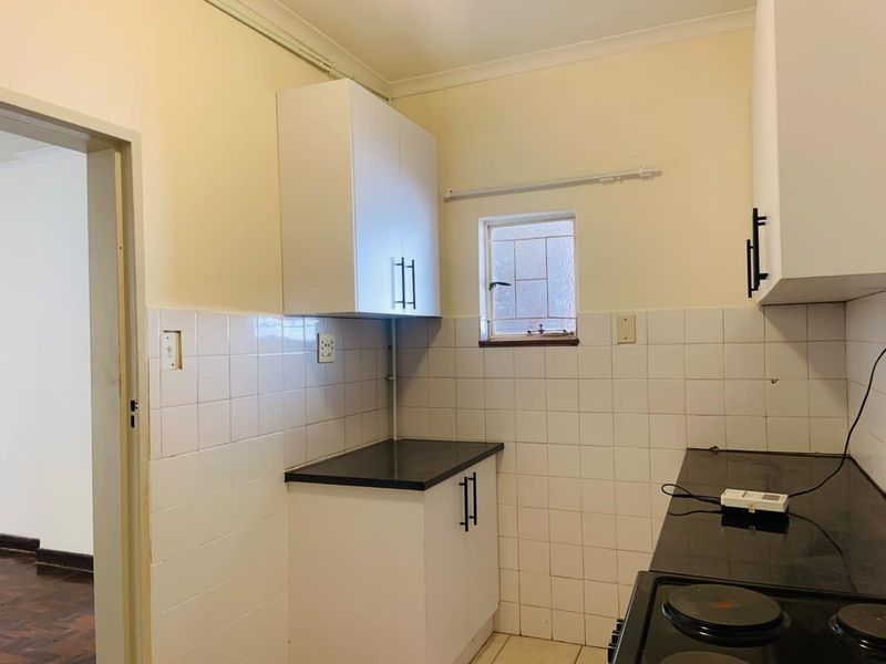 A functional kitchen featuring white cabinetry, dark countertops, and tiled splashbacks, providing a clean and practical workspace.