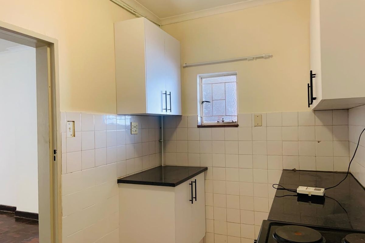 A functional kitchen featuring white cabinetry, dark countertops, and tiled splashbacks, providing a clean and practical workspace.