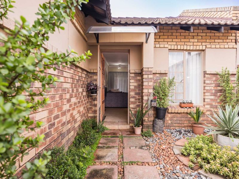 Front entrance of the townhouse featuring a face brick facade, tiled roof, and a paved walkway leading to the front door.