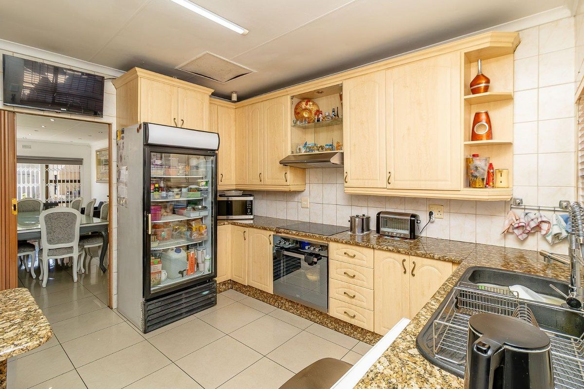 Functional kitchen featuring light wood cabinetry, granite countertops, integrated appliances, and tiled flooring, with direct access to the adjacent dining area.