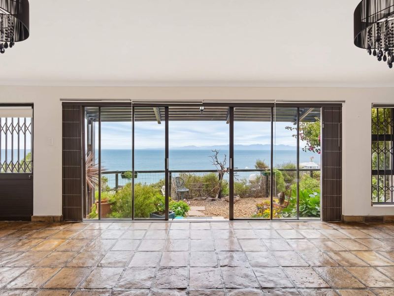 Spacious living area featuring large sliding glass doors that open to a scenic ocean view, complemented by durable tiled flooring and neutral walls.