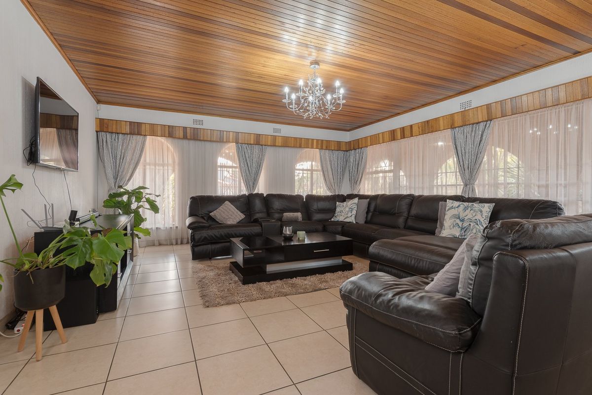 Spacious living room featuring a distinctive timber-clad ceiling, tiled flooring, and large arched windows that provide ample natural light.