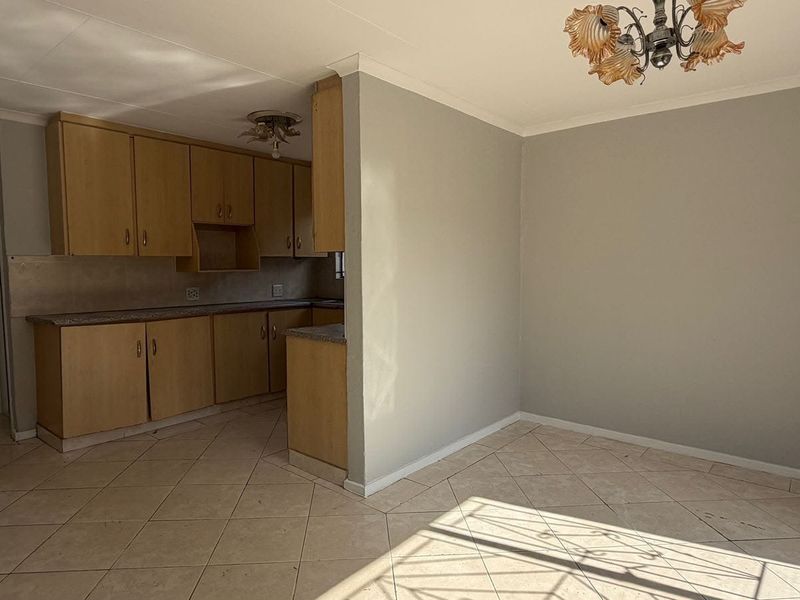 Open-plan kitchen and dining area featuring tiled flooring, neutral walls, and functional laminate cabinetry, offering a blank canvas for modern updates.