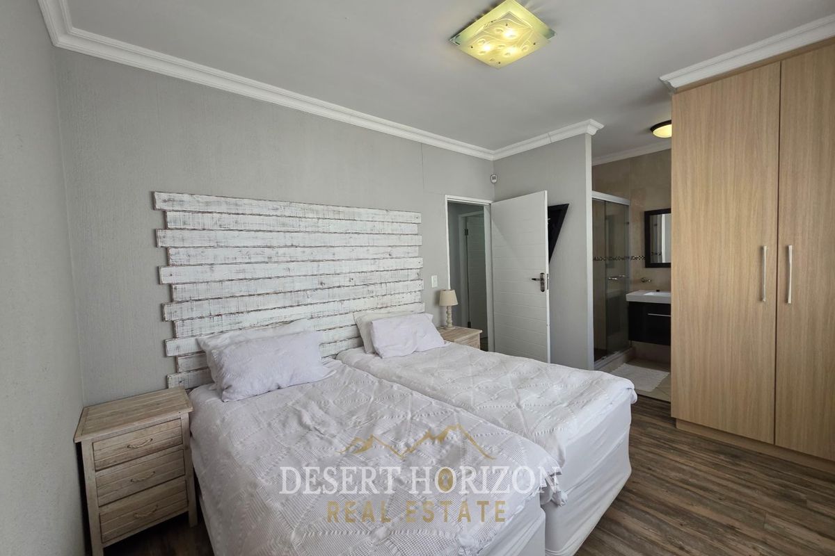 A well-maintained bedroom featuring laminate flooring, a built-in wardrobe, and an attached en-suite bathroom with a shower.