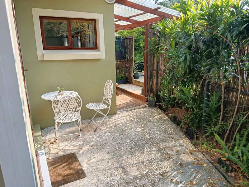A compact outdoor patio area featuring a timber pergola, decking, and privacy screening, providing a cozy space for outdoor relaxation.