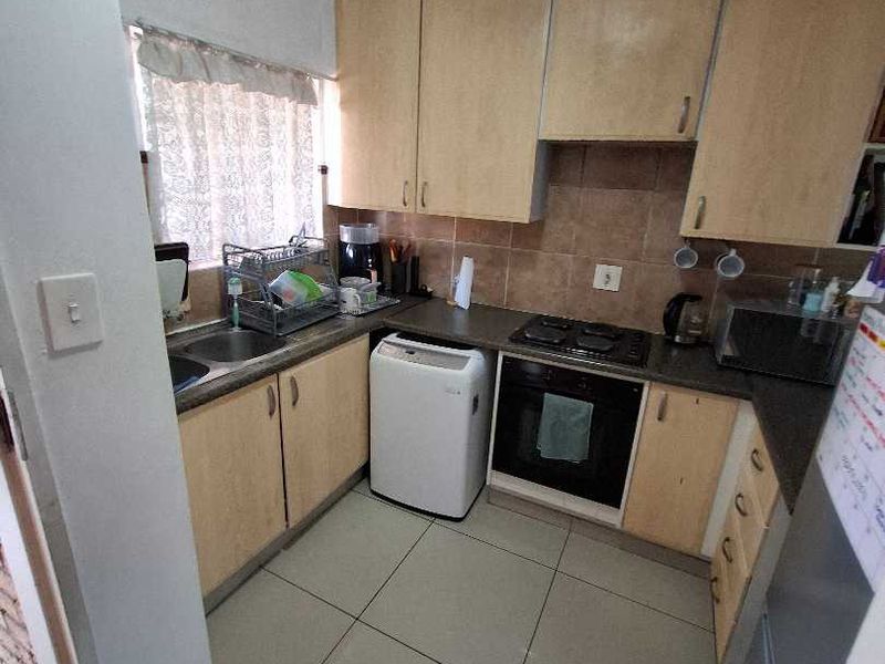 Compact kitchen featuring laminate cabinetry, built-in oven, gas hob, and tiled flooring. The space offers functional storage and preparation areas.