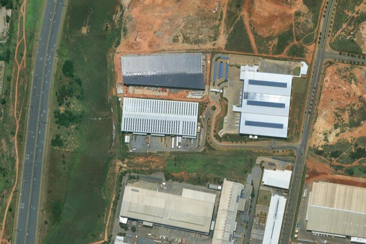 Aerial view of a large industrial park featuring multiple warehouse facilities, expansive paved loading areas, and direct access to major road infrastructure.