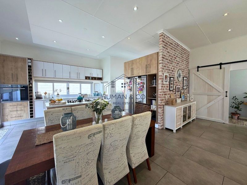 Spacious open-plan kitchen and dining area featuring a striking exposed brick wall, modern cabinetry, and a functional kitchen island with integrated appliances.