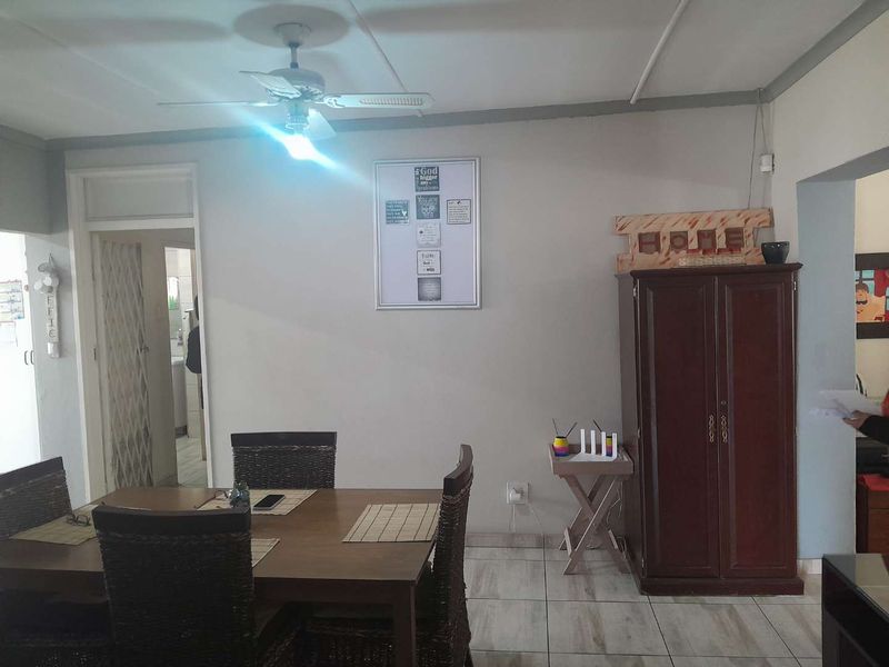 A functional dining area featuring tiled flooring and a ceiling fan, providing a neutral space for family meals.
