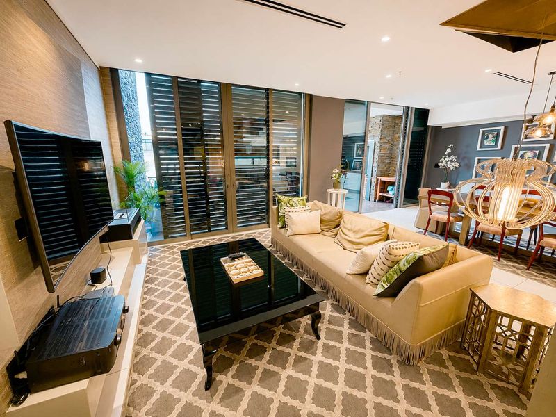 Modern open-plan living area featuring recessed lighting, stone accent wall, and large sliding glass doors leading to an outdoor space.
