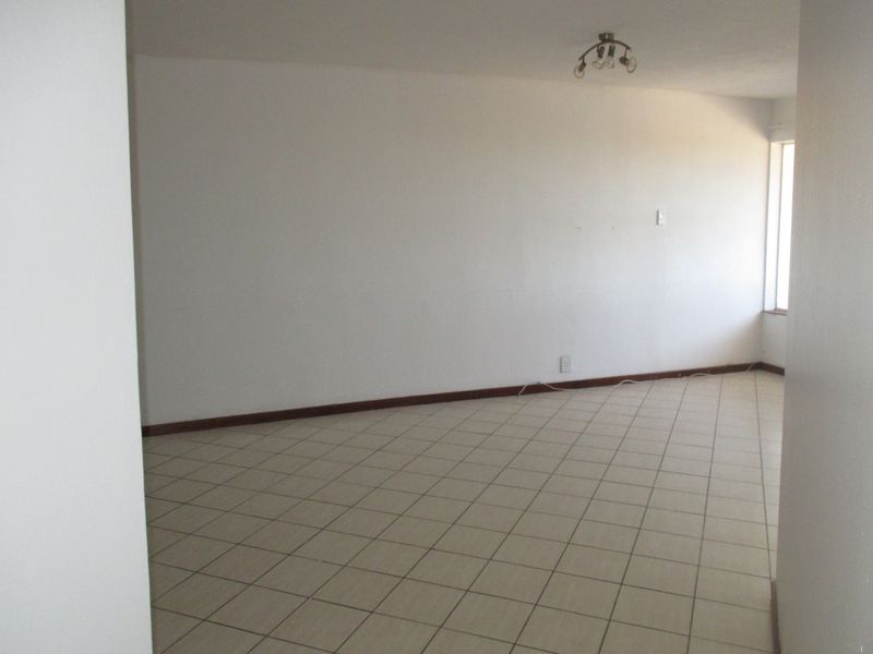 A spacious, empty living area featuring neutral tiled flooring and a simple ceiling light fixture, ready for personalization.