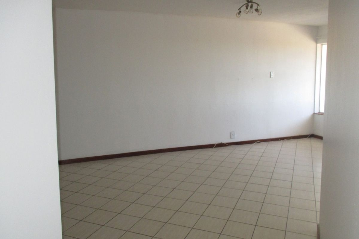A spacious, empty living area featuring neutral tiled flooring and a simple ceiling light fixture, ready for personalization.